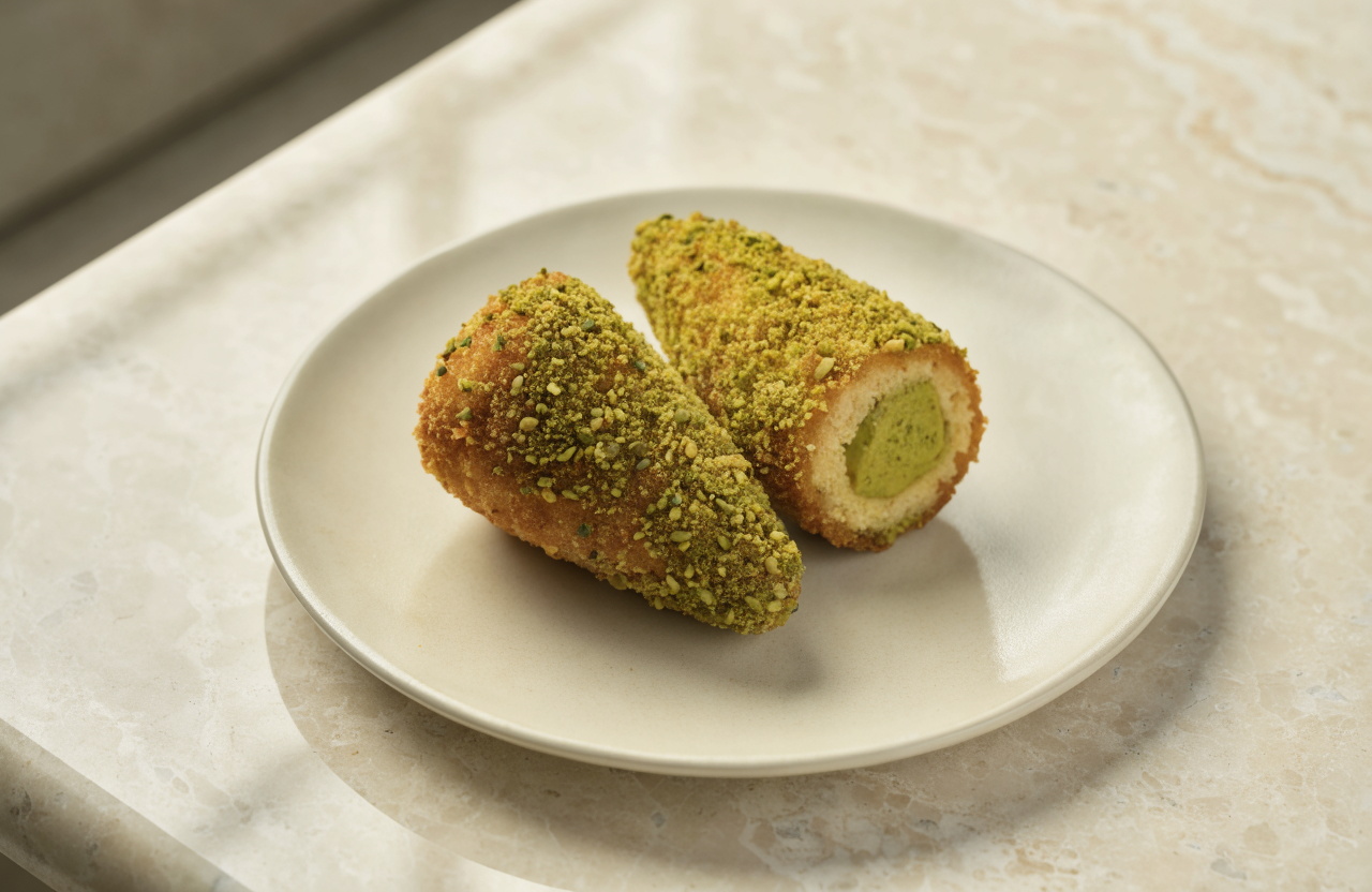 Arancini al pistacchio con granella, uno aperto sul ripieno verde